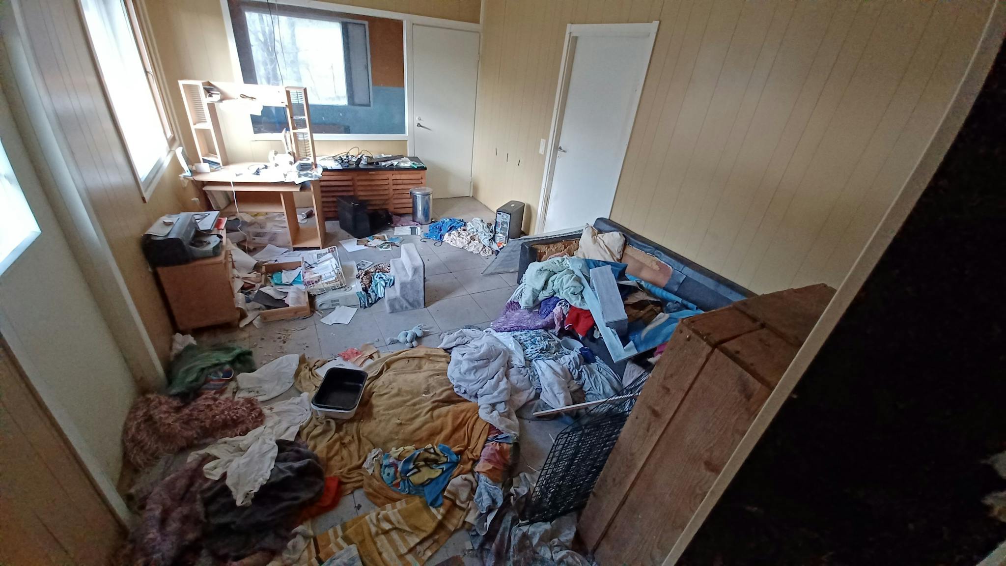 Keltainen huone, jossa on työpöytä ja tulostin, maassa paljon tekstiilejä ja eläintentarvikkeita