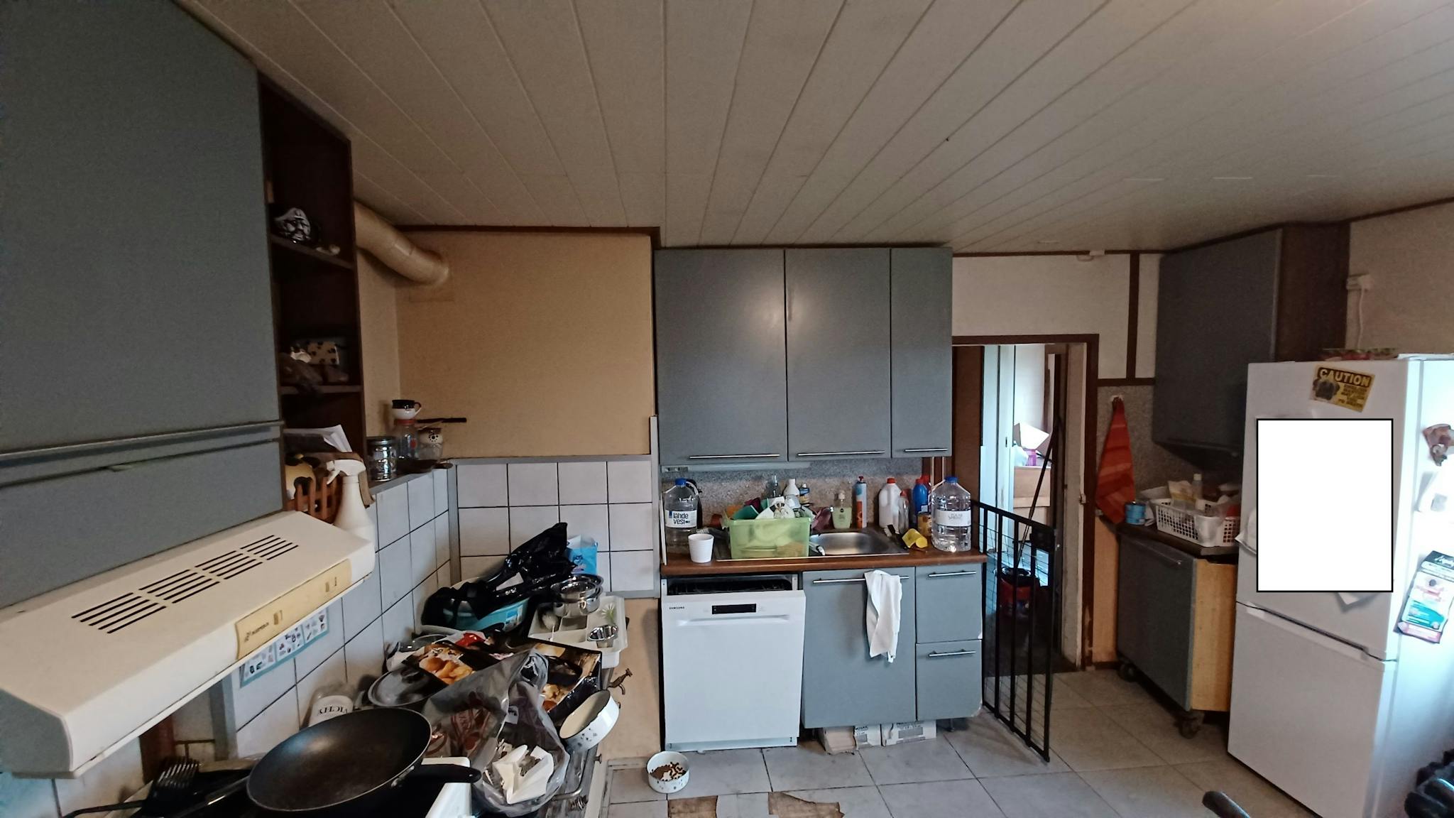 Keittiö ulkoseinältä kuvattuna. Seinustalla tiskikkone ja kaappitilaa. Oikealla jääkaappi-pakastin.