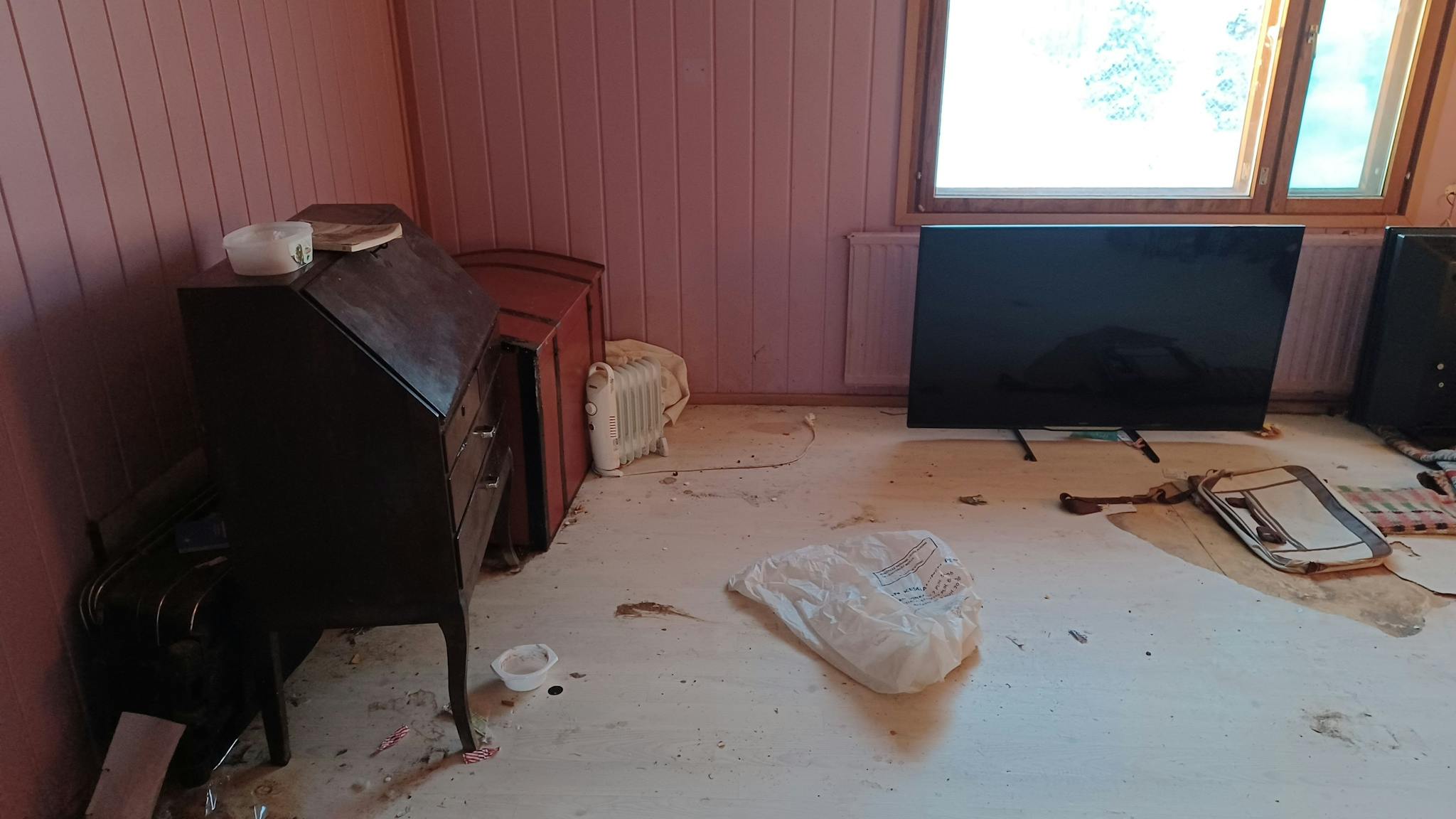 Vaaleanpunainen huone, jossa televisio ja klaffikaappi