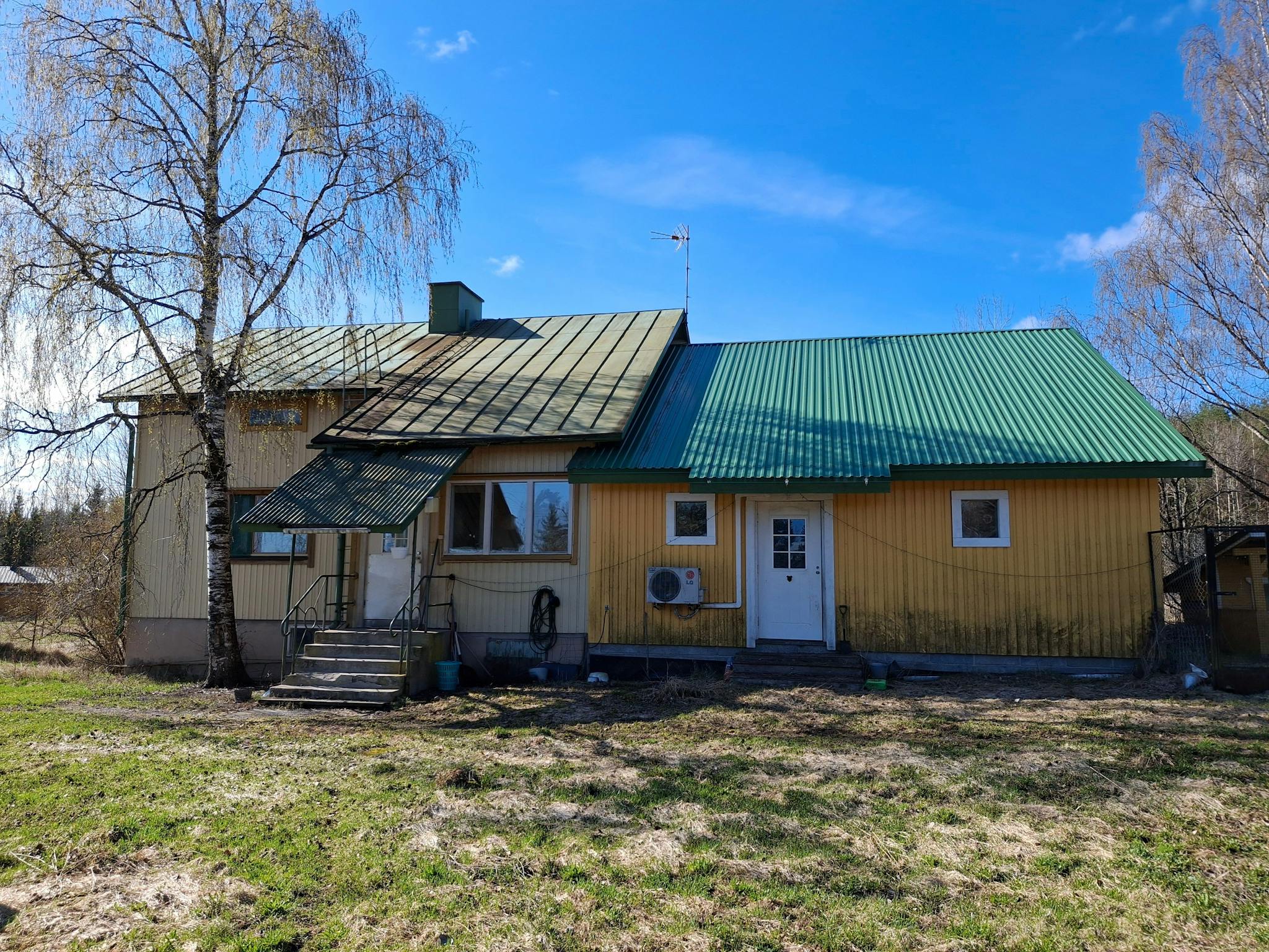 Asuinrakennus edestä kuvattuna. Talon edessä kasvaa koivu.