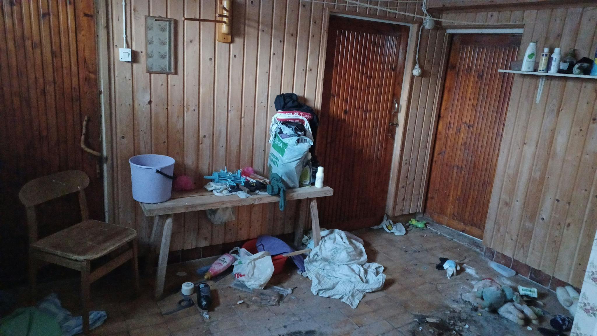 Paneloitu huone, jossa kolme ovea ja penkki. Mahdollisesti pukeutumista varten.