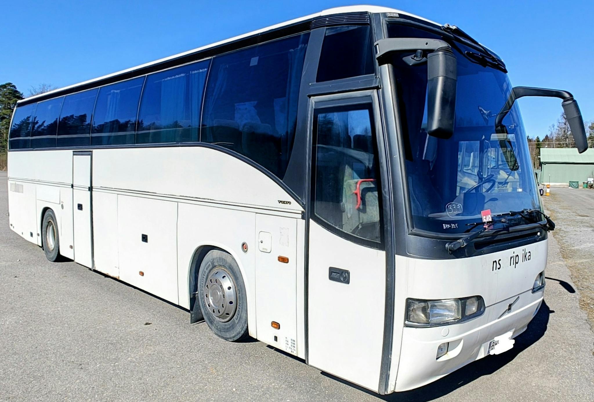 Valkoinen linja-auto etukulmasta kuvattuna