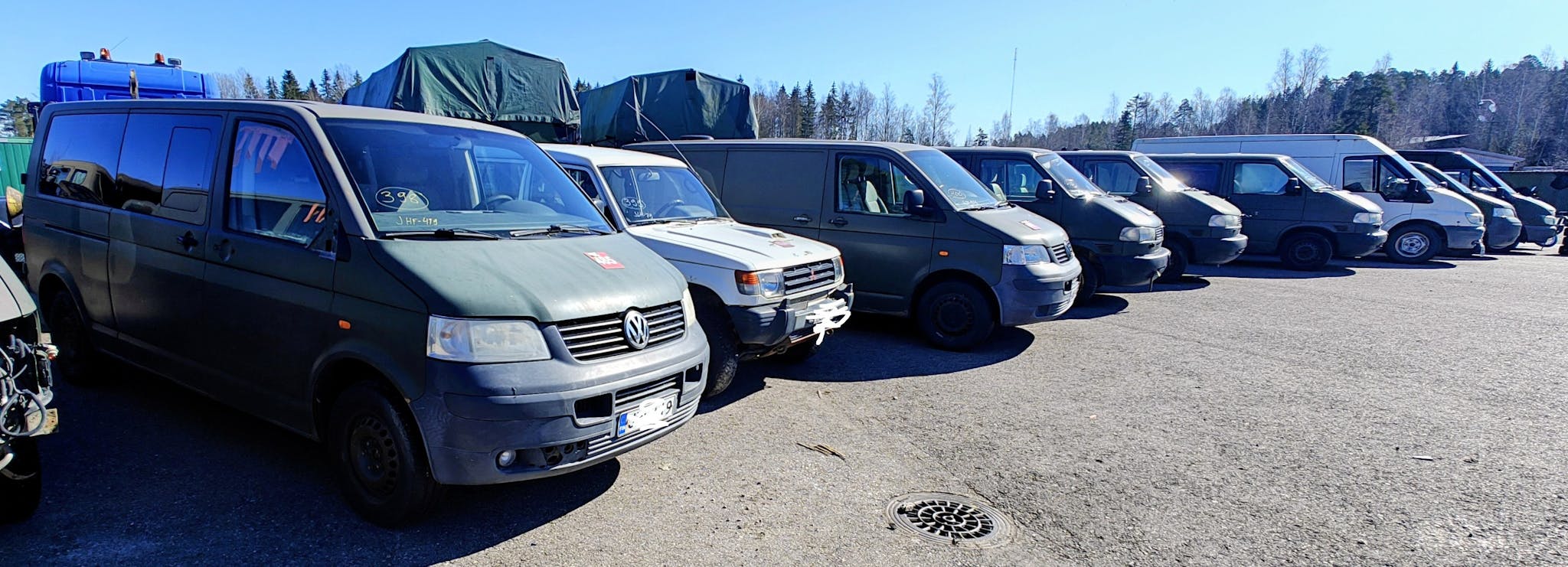 Valkoisia ja vihreitä pakettiautoja rivissä