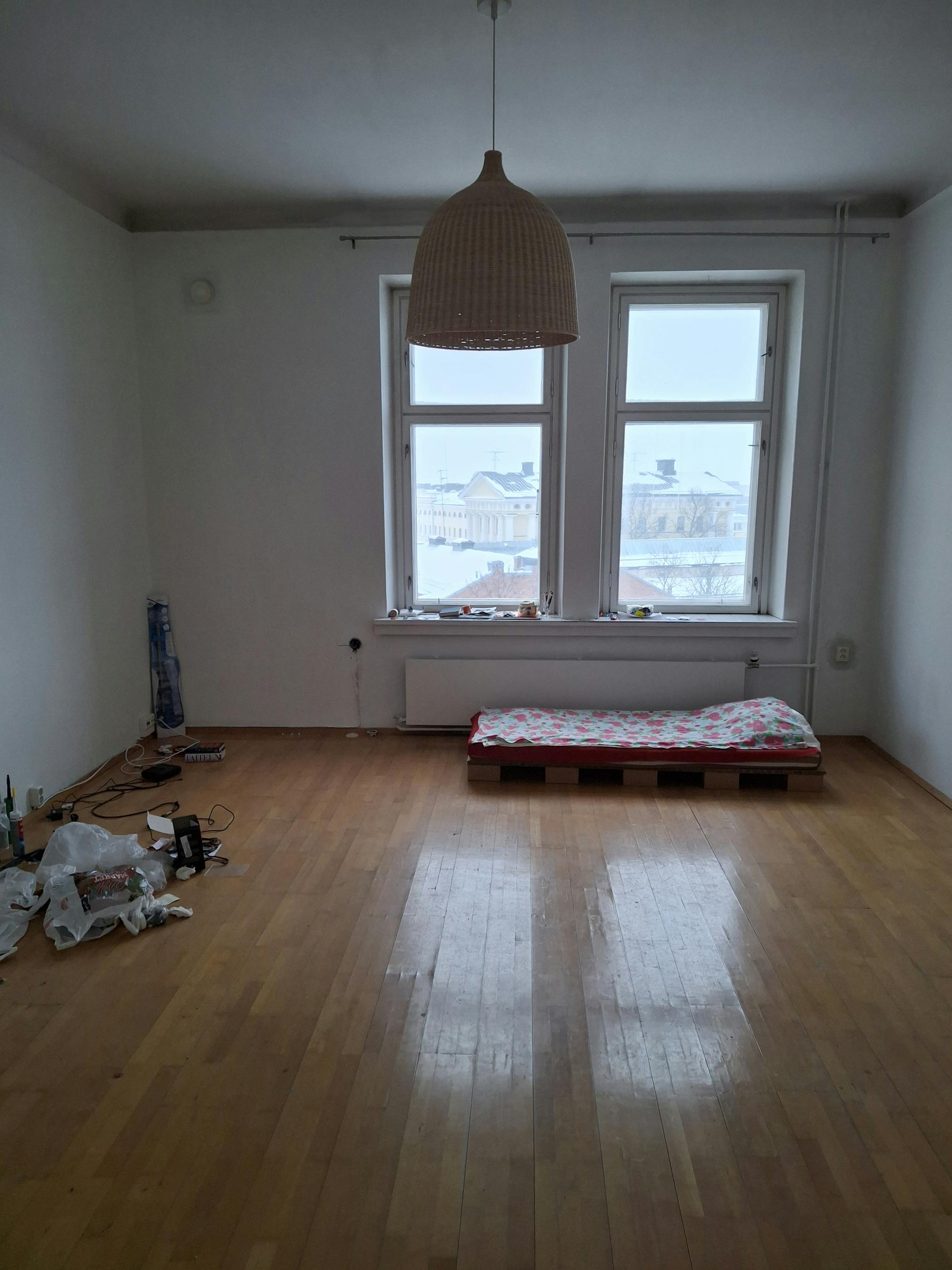 Huone, jossa on pari-ikkuna ja sen alla lämpöpatteri. Lattiat ovat parkettia