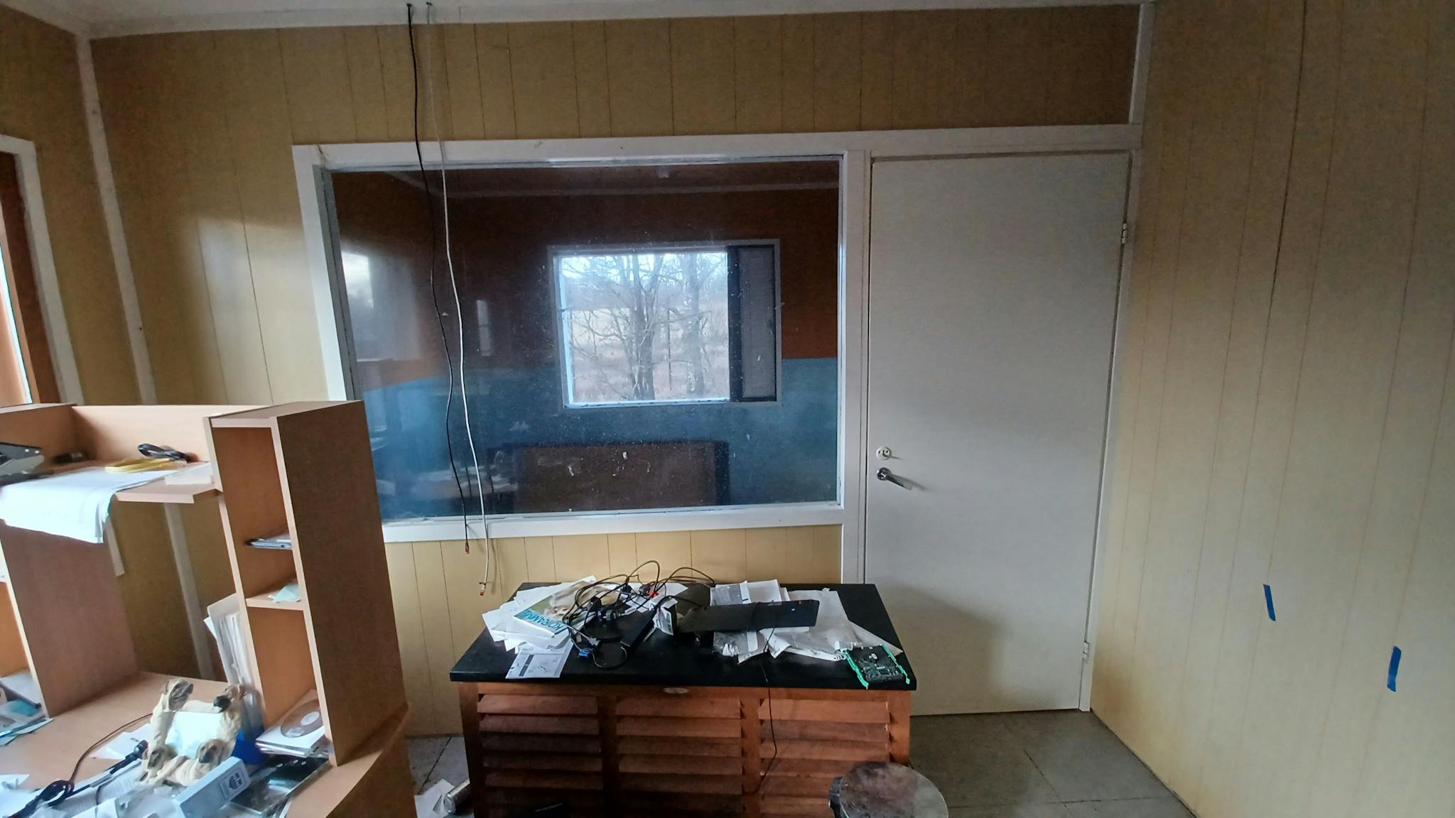 Kuva keltaisessa huoneessa olevasta ikkunasta ja ovesta, joiden takana on eläintenpidossa käytetty huone.